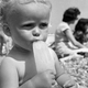 Black and white photo of baby eating popsicle on the beach
